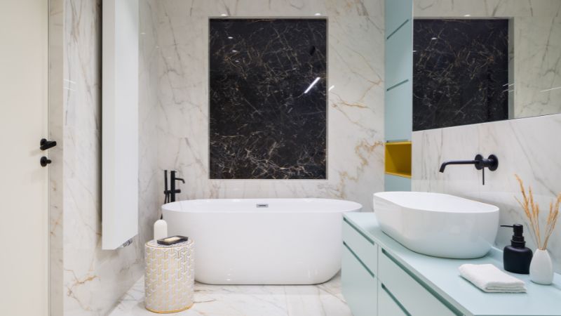 salle de bain rénovée, avec détails de marbre et meuble sous-lavabo turquoise, illustrant les compétences d'un bon artisan