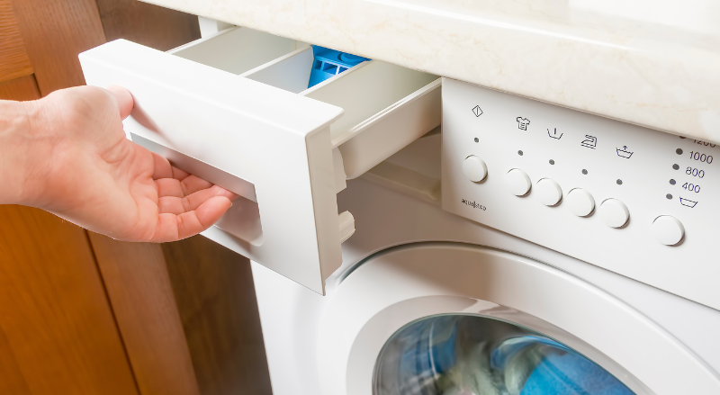 une femme ouvre le bac a lessive d une machine a laver 