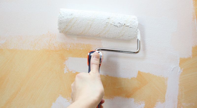 peindre un mur jaune en tadelakt avec un rouleau de peinture blanche