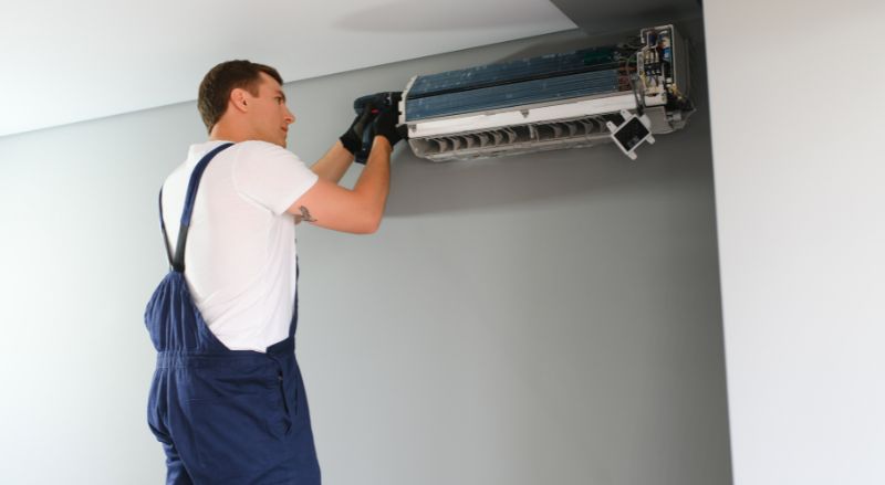 technicien reparant un climatiseur mural