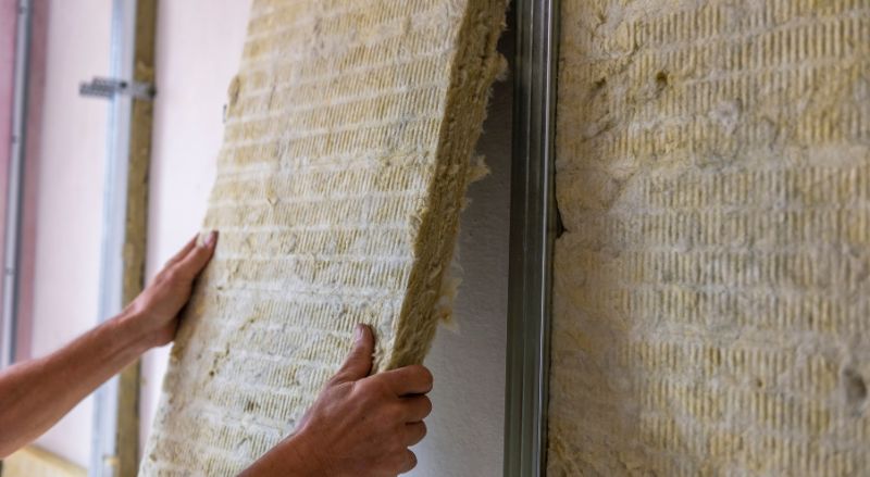 artisan isolant un mur de piece avec une isolation acoustique et thermique en laine de roche minerale.