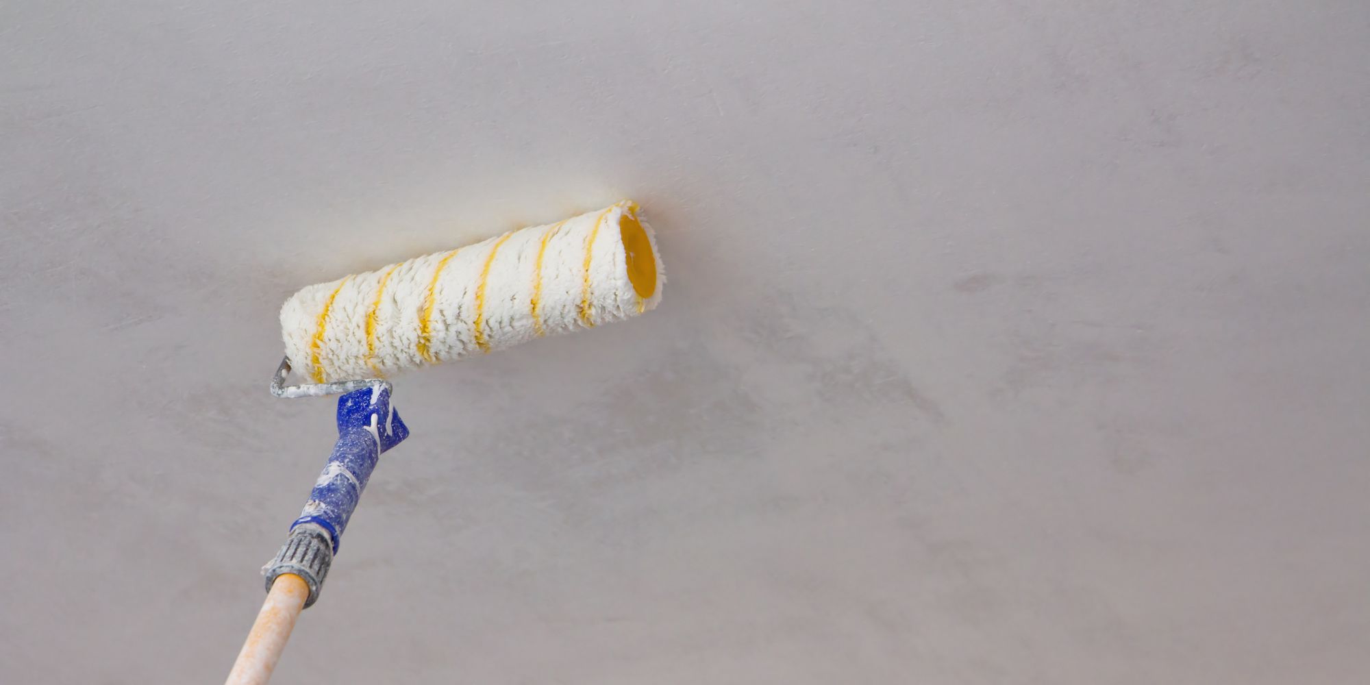 Personne qui peint un plafond avec un rouleau.