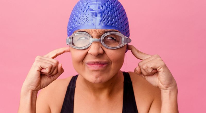 nageuse equipee d un bonnet de bain et de lunettes de plongee se bouchant les oreilles
