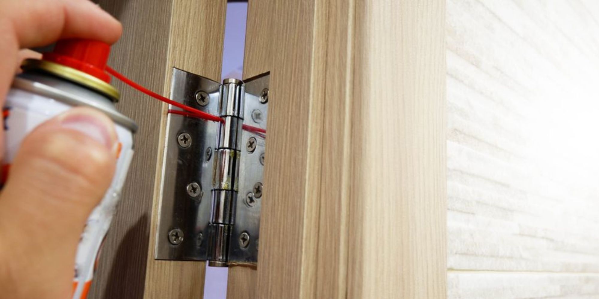 Personne qui met du WD-40 sur les charnières de porte 