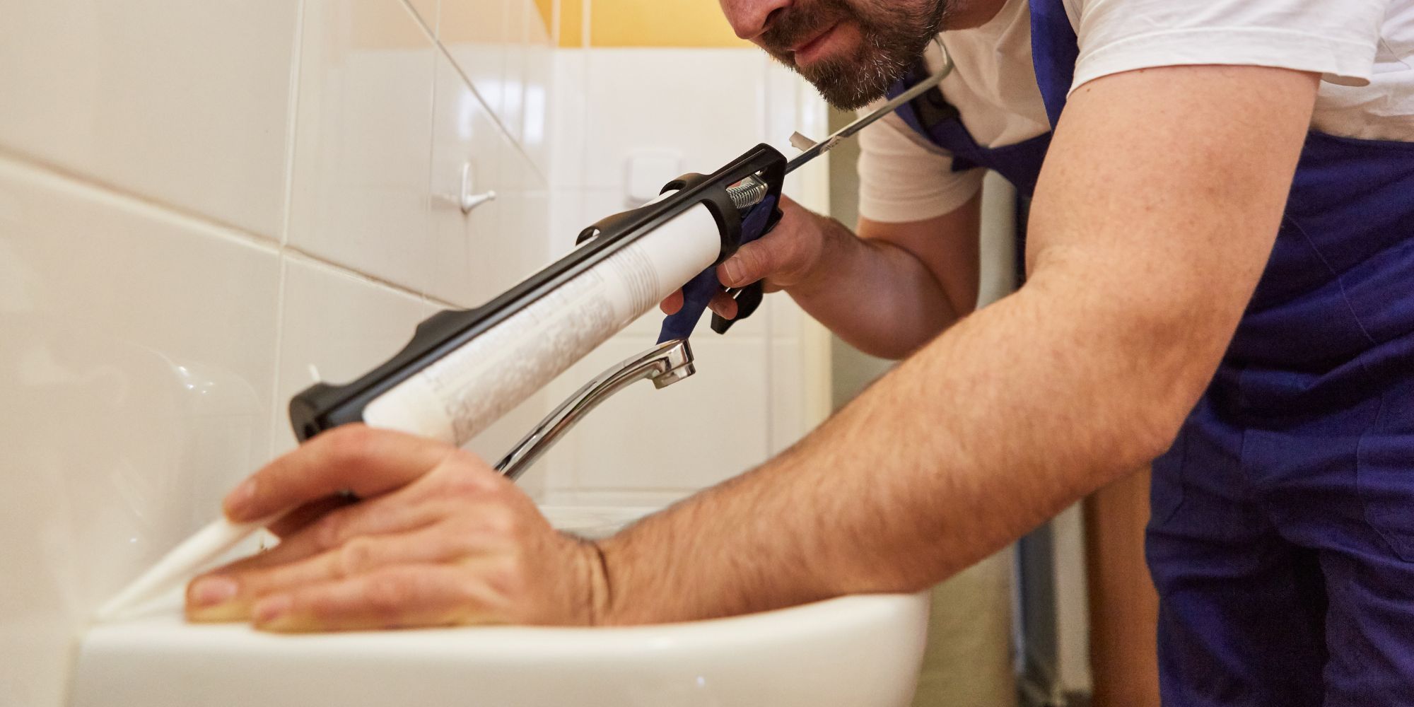 Artisan qui fait des joints silicone dans une salle de bain