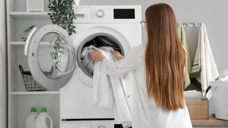 jeune femme mettant des vetements dans un seche linge 