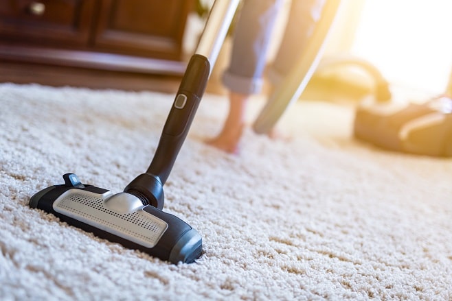Personne qui nettoie sa moquette avec un aspirateur