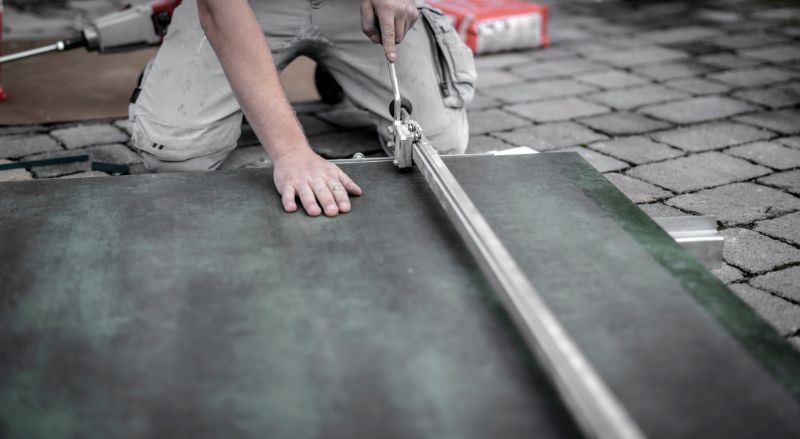 artisan en train de decouper un carrelage grand format 120x140 pour suggerer l idee du prix pour la pose de ce revetement particulier