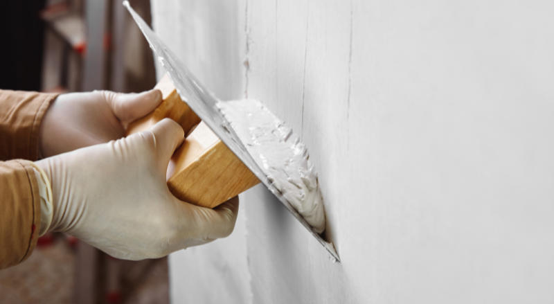 gros plan sur les mains d un ouvrier du batiment en train de platrer et de lisser le mur avec une truelle derniere etape pour un mur ponce parfait