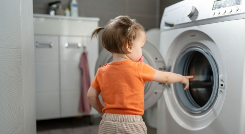 Enfant devant une porte de lave-linge 
