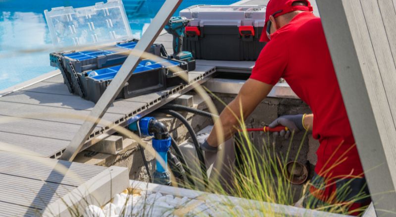 homme reparant un moteur de piscine encastre dans le sol