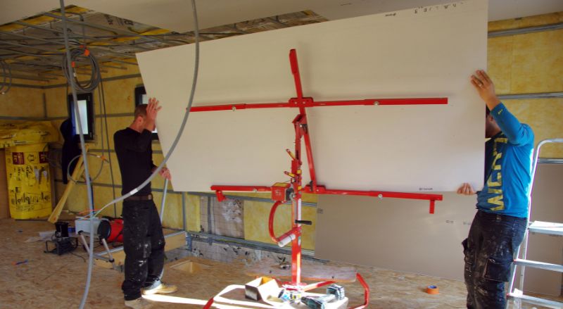 deux artisans utilisant un leve plaque pour poser du placo au plafond