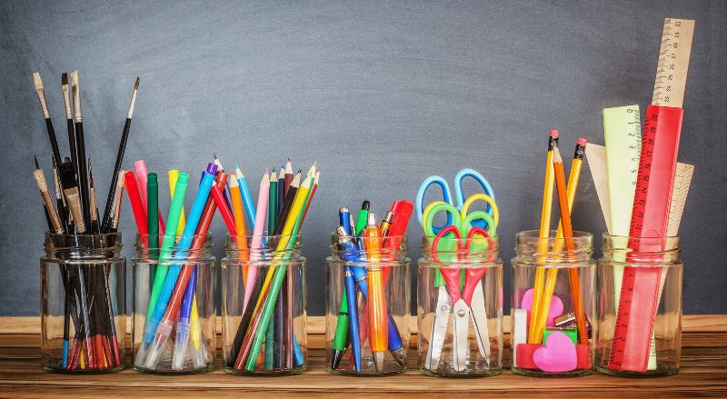 fournitures scolaires dans des bocaux contre un tableau noir