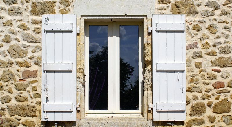 volets blancs sur une maison en pierre